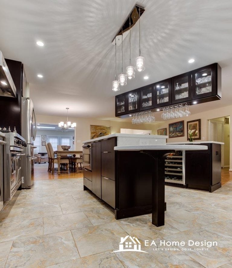 A view of a renovated kitchen with a focus on the appliances. A large, white refrigerator is visible on the far left, while a white microwave and stove stand out in the center and to the right. The countertops are a light, solid color, complementing the creamy white cabinets.