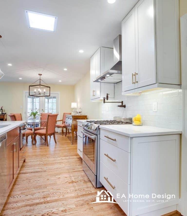 A close-up view of the stovetop area in a kitchen. The white flat-top electric stove is in the foreground, with a matching microwave mounted above it. The backsplash behind the stove is made of small, stacked, light-colored tiles.