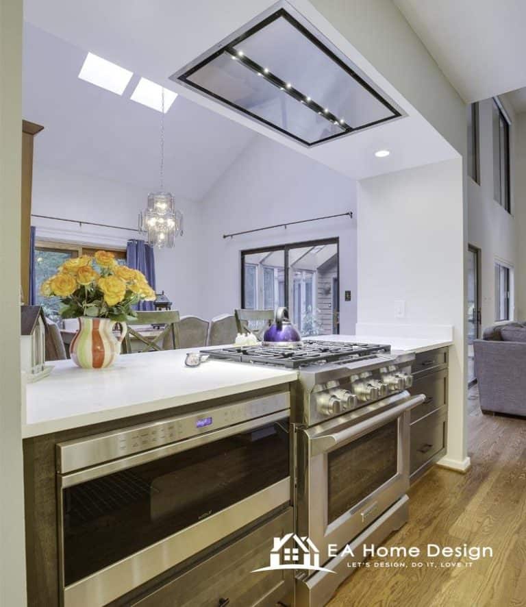 An angled shot of a kitchen, highlighting the corner sink and a modern stove, with the fridge visible on the far wall and a dining area to the side.