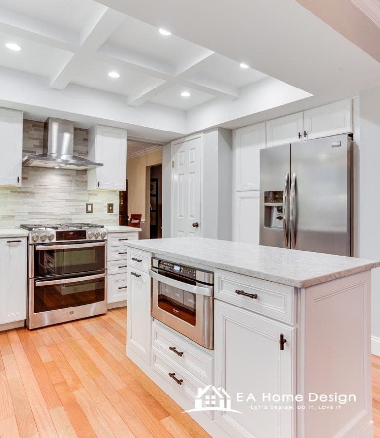 A photograph highlighting the details of a modern kitchen. The countertops are clear of clutter, save for a toaster and some glass jars. The hardware on the cabinets and drawers is a dark bronze or black, providing a subtle contrast to the white cabinetry.