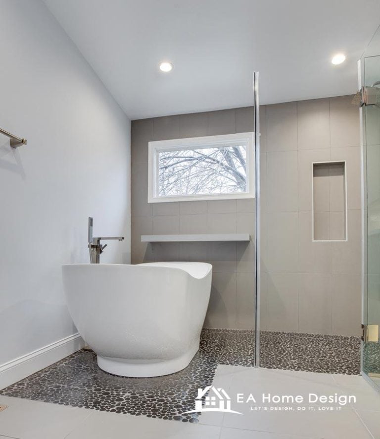 A stylish bathroom with a freestanding tub, dark hexagon tile floor, and a double vanity with open storage for towels.