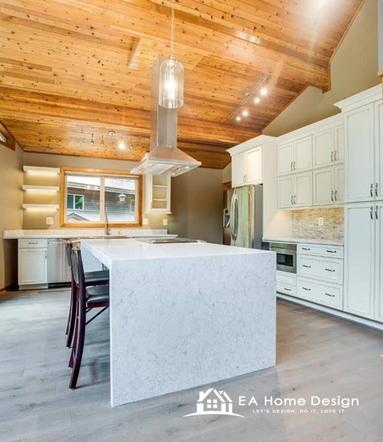 A slightly elevated view of a kitchen and dining area. The image captures the full length of the space, from the breakfast bar in the foreground to the dining table at the back. The consistent use of wood for the floors and cabinets gives the room a cohesive, inviting look.