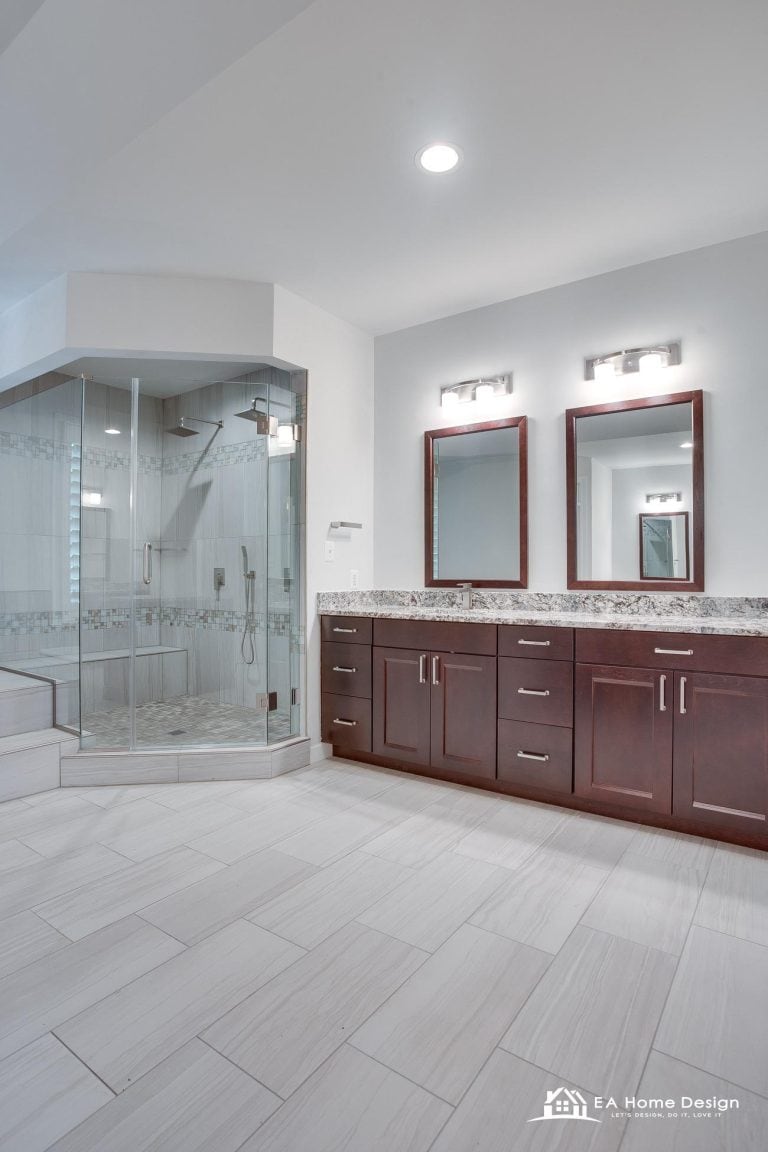 Shower and bathroom vanity with gold accents, white cabinets, and beige tiles.