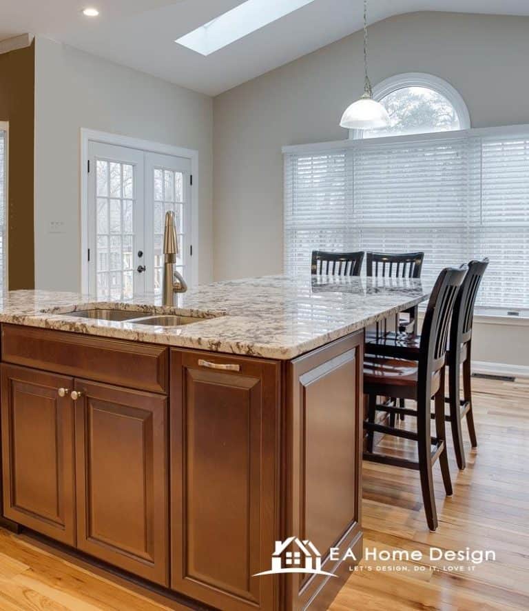 An interior photograph showing the transition from a living area to a kitchen. On the right, a built-in entertainment unit with a fireplace and shelving is partially visible. The central focus is the pale wood flooring leading toward a dark, modern kitchen in the background.