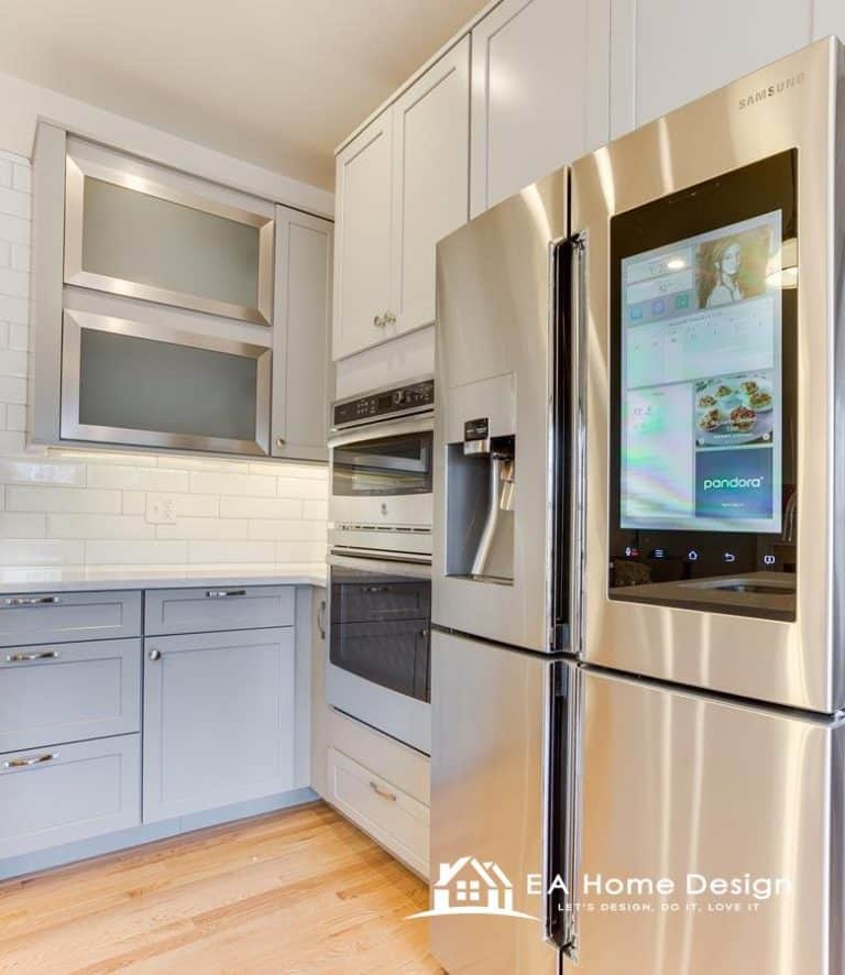 An interior photograph of a kitchen, emphasizing the seamless integration of appliances. The white refrigerator, microwave, and stove blend in with the surrounding cabinetry, creating a clean and unified look. The dark cabinet pulls are a noticeable design detail.