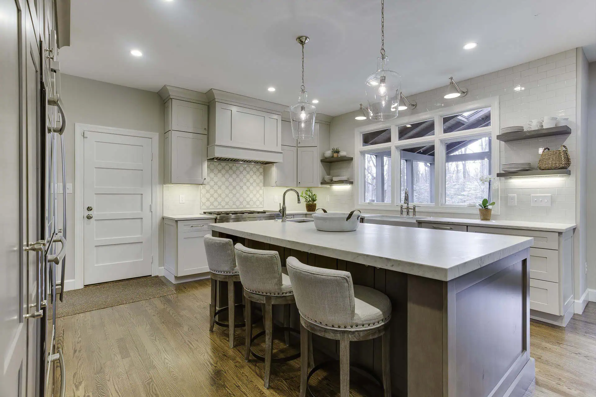 Northern Virginia kitchen with grey island, white cabinets, glass pendant lights and upholstered bar stools