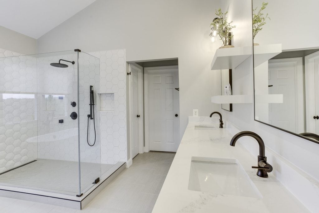 Modern marble bathroom with tub, shower, toilet, and gold accents.