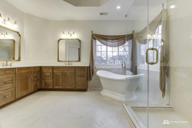 Modern marble bathroom with tub, shower, toilet, and gold accents