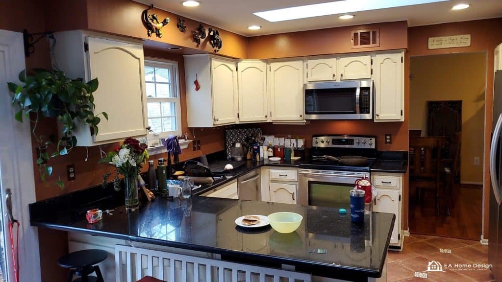 A close-up of a kitchen sink with visible pipes, surrounded by a clean counter, with a glimpse of a modern stove and fridge in the background.