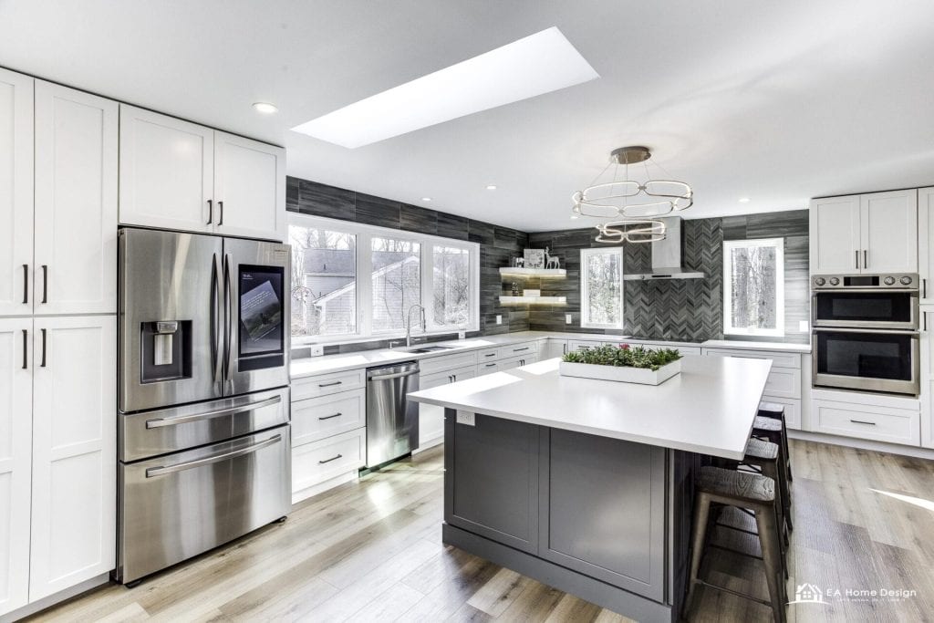 Contemporary kitchen with white cabinetry, black island, stainless steel appliances, and wood flooring.