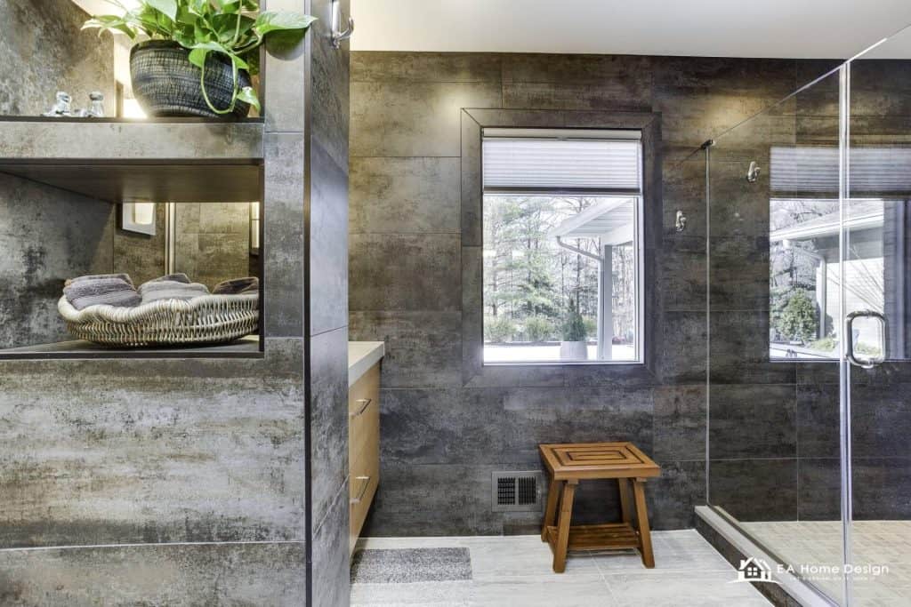 Modern bathroom with textured gray tiles and a large window overlooking a snowy landscape