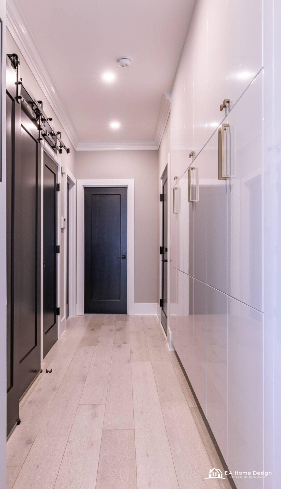 Small hallway remodel in Northern Virginia with white built-in cabinetry, black barn doors and wide plank light wood flooring