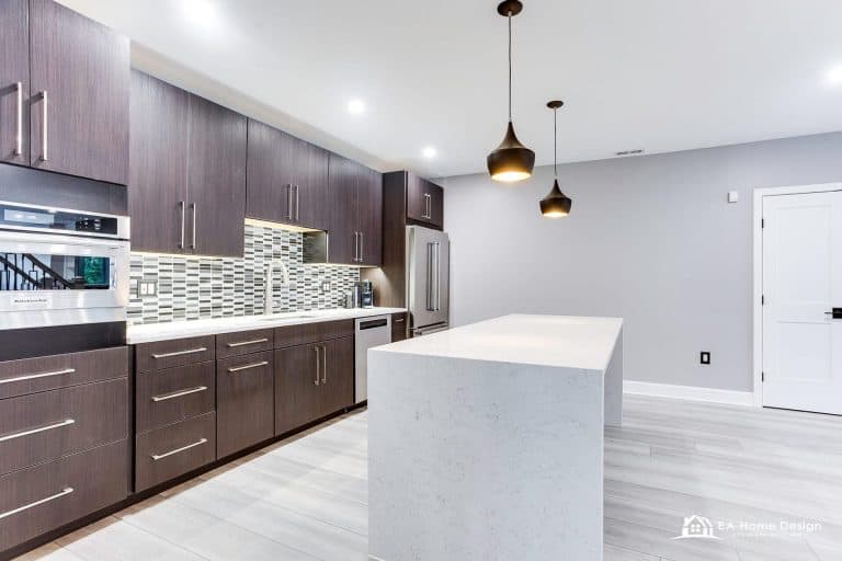 Modern kitchen with dark wood cabinets, mosaic tile backsplash, and a large white island.