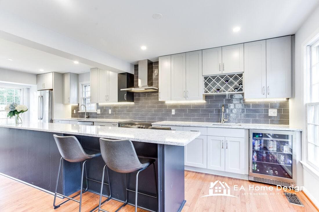 After photo of the same Reston galley kitchen remodel with white shaker cabinets, navy island with bar stools and grey subway tile