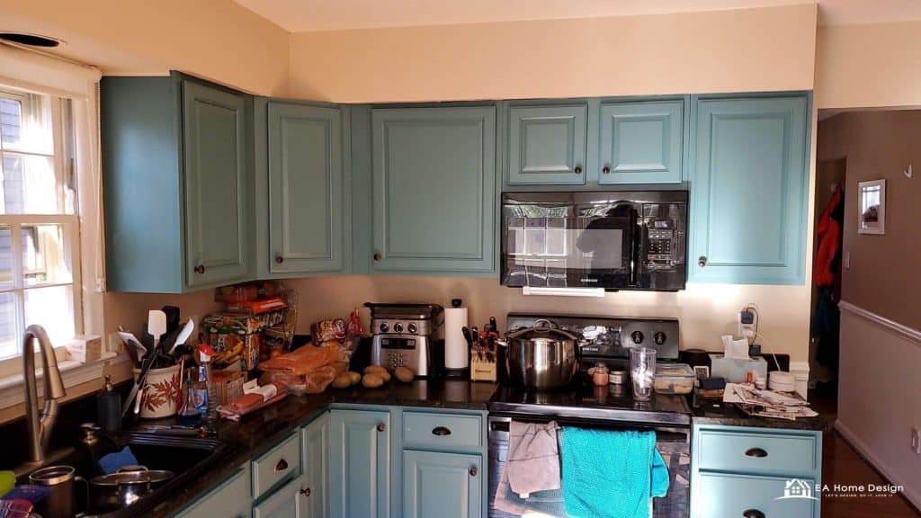 Colorful kitchen with blue cabinets, black appliances, and cluttered countertops in a cozy home setting.