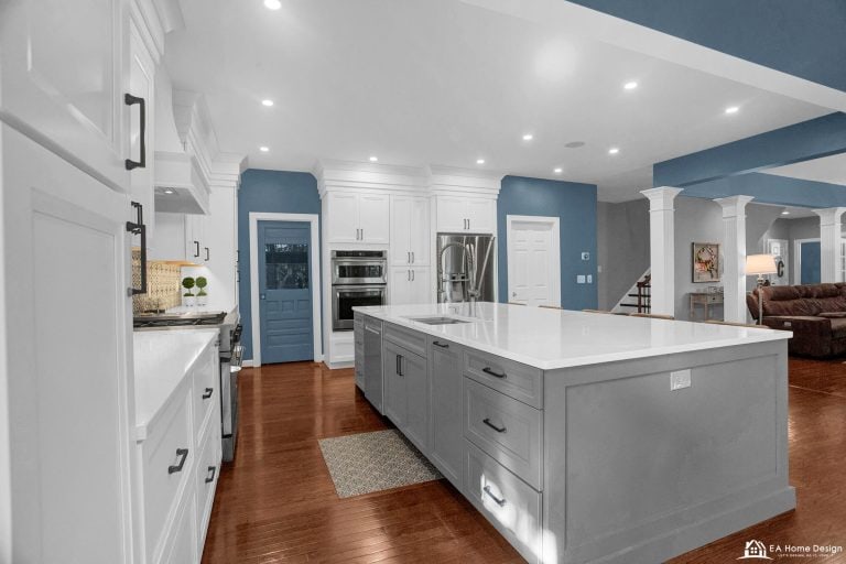 A full view of a spacious kitchen with a dining island, a built-in fridge, and a professional-grade stove, all illuminated by stylish overhead lighting.