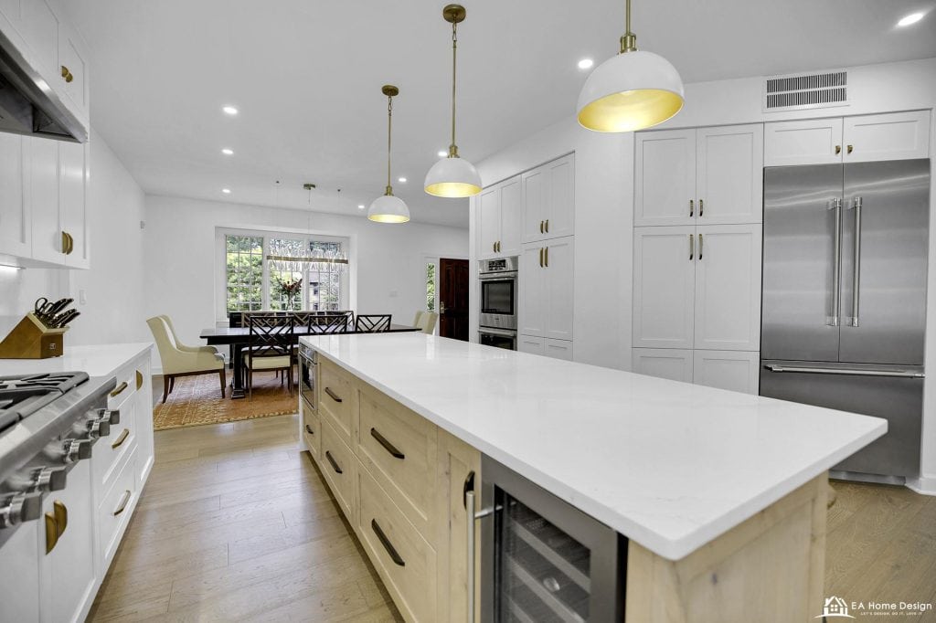 Modern white kitchen with large island, stainless steel appliances, and elegant lighting, perfect for contemporary home living.