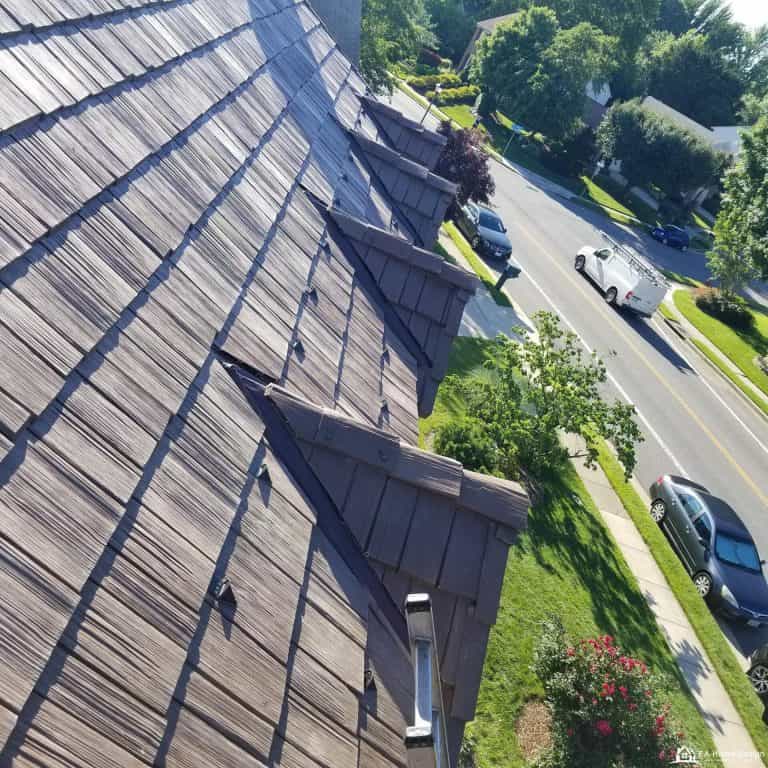 Rooftop view of residential neighborhood with trees and parked cars.
