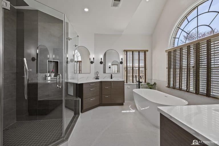 Modern marble bathroom with tub, shower, toilet, and gold accents.