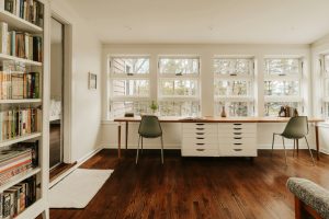 Bright home office with large windows, a long desk, and bookshelves—ideal for closet conversions.