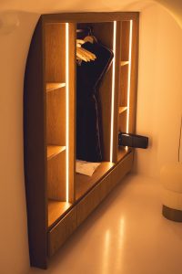 A modern wooden wardrobe features shelves and built-in lights, ideal for clever closet conversions.