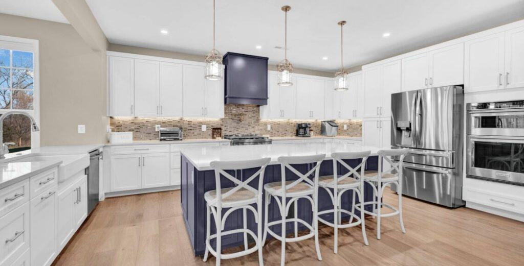 Modern white and navy kitchen with stainless steel appliances and central island for family cooking and entertaining purposes.