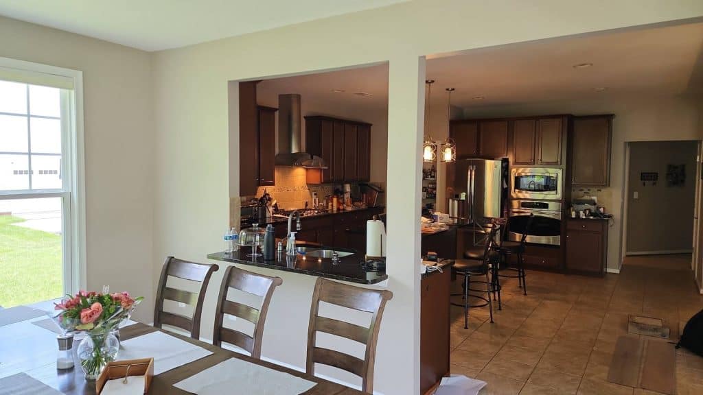 A full view of a spacious kitchen with a dining island, a built-in fridge, and a professional-grade stove, all illuminated by stylish overhead lighting.