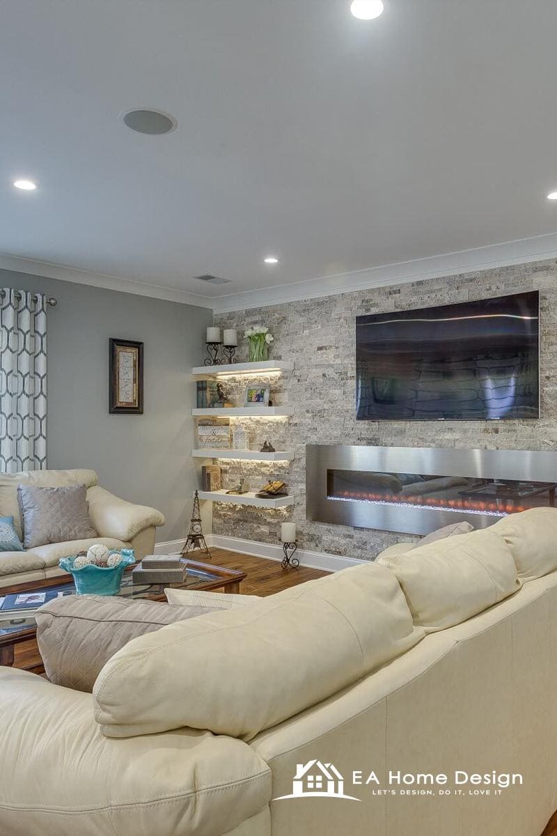 A minimal yet elegant living room with a reflective wall of mirrors that makes the space feel larger. The room is furnished with two cream couches, a small table, and a black grand piano, and it flows into a slightly elevated dining area.