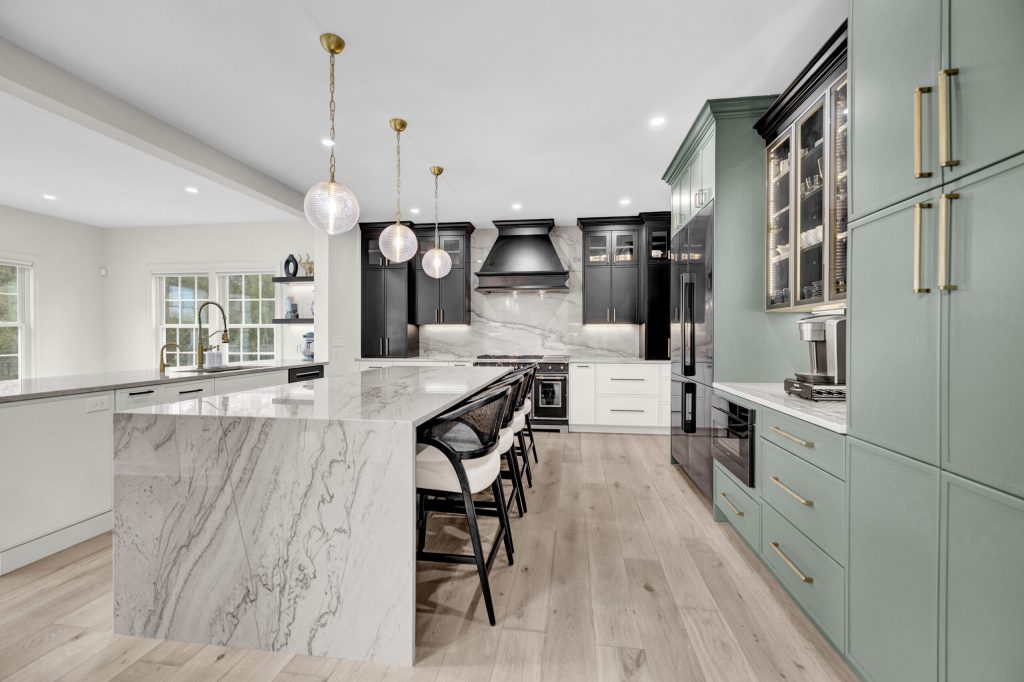 After: black and sage green Crystal cabinetry, quartzite waterfall island, brass pendants and light hardwood