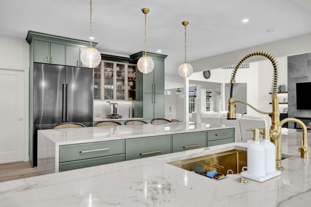 After: the quartzite island with a brass faucet and stools, open to the family room