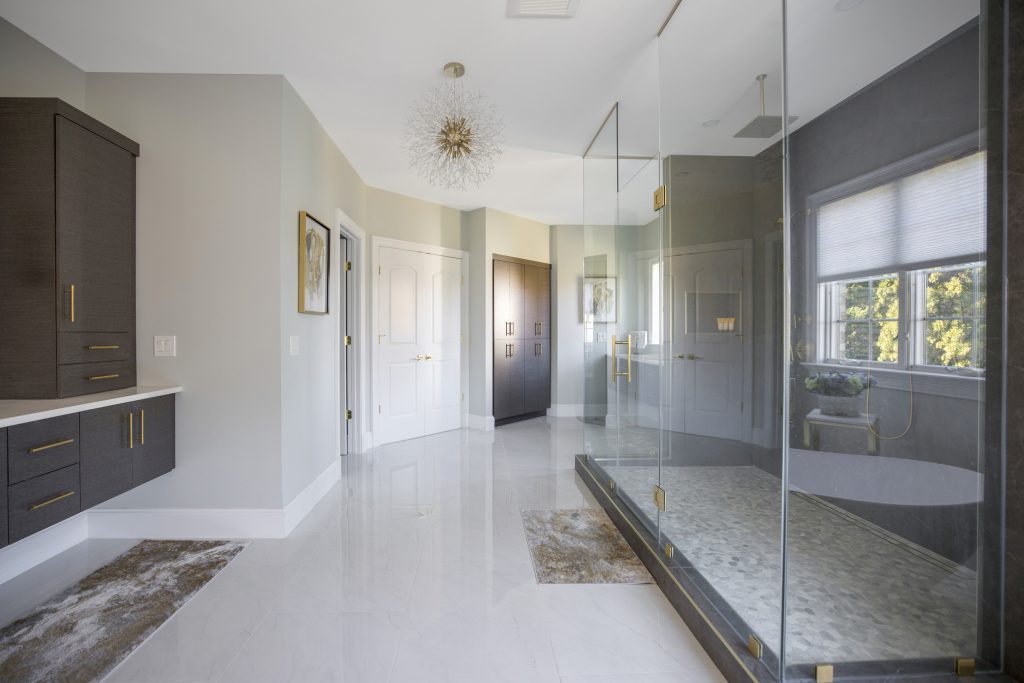 After: wide view of the finished Great Falls primary bathroom with vanity, shower and chandelier