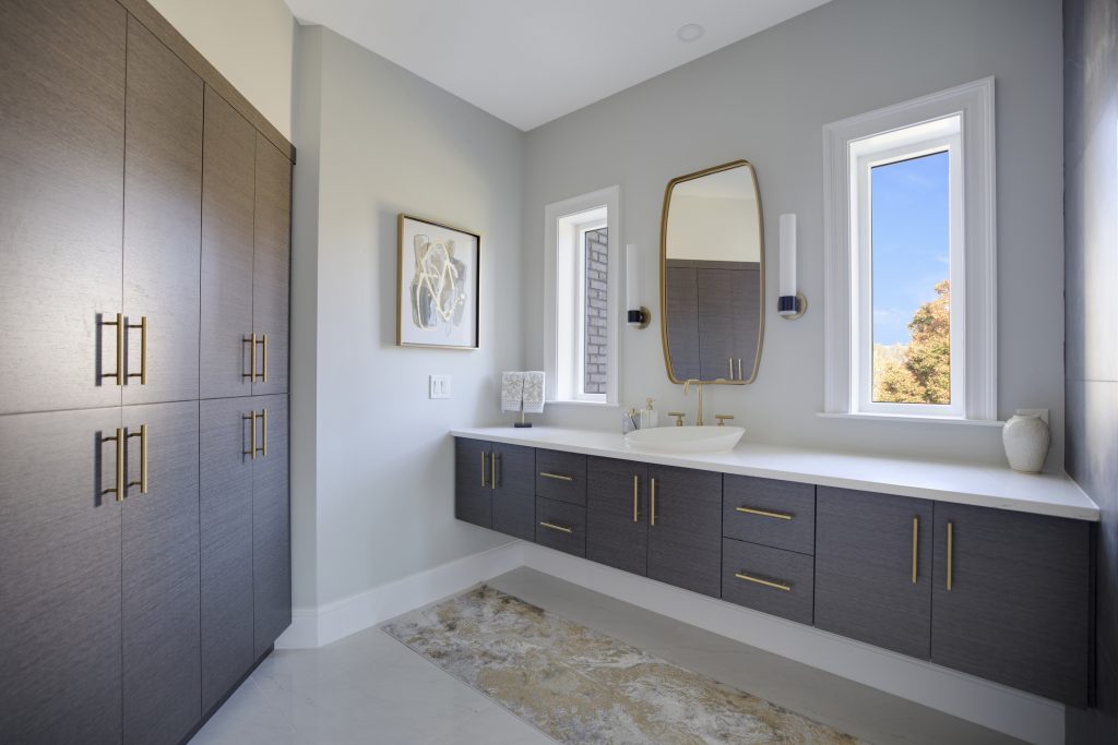 After: floating gray oak vanity with gold framed mirror between two windows