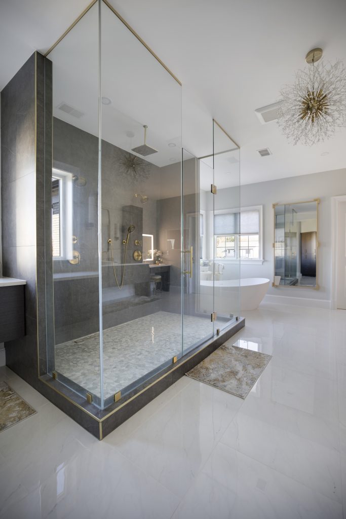 After: the walk-in shower corner with gold trim and the tub beyond