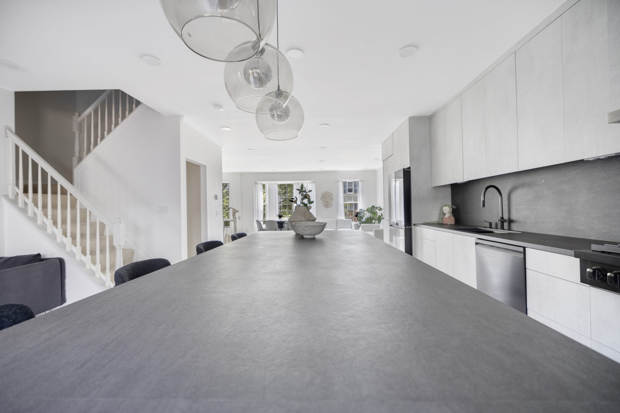 Modern minimalist white kitchen with black accents and island in contemporary home interior.