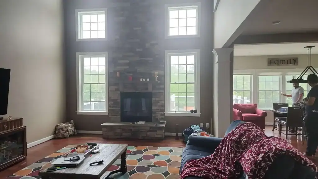 Before: two storey family room with a stone fireplace and posts dividing it from the kitchen
