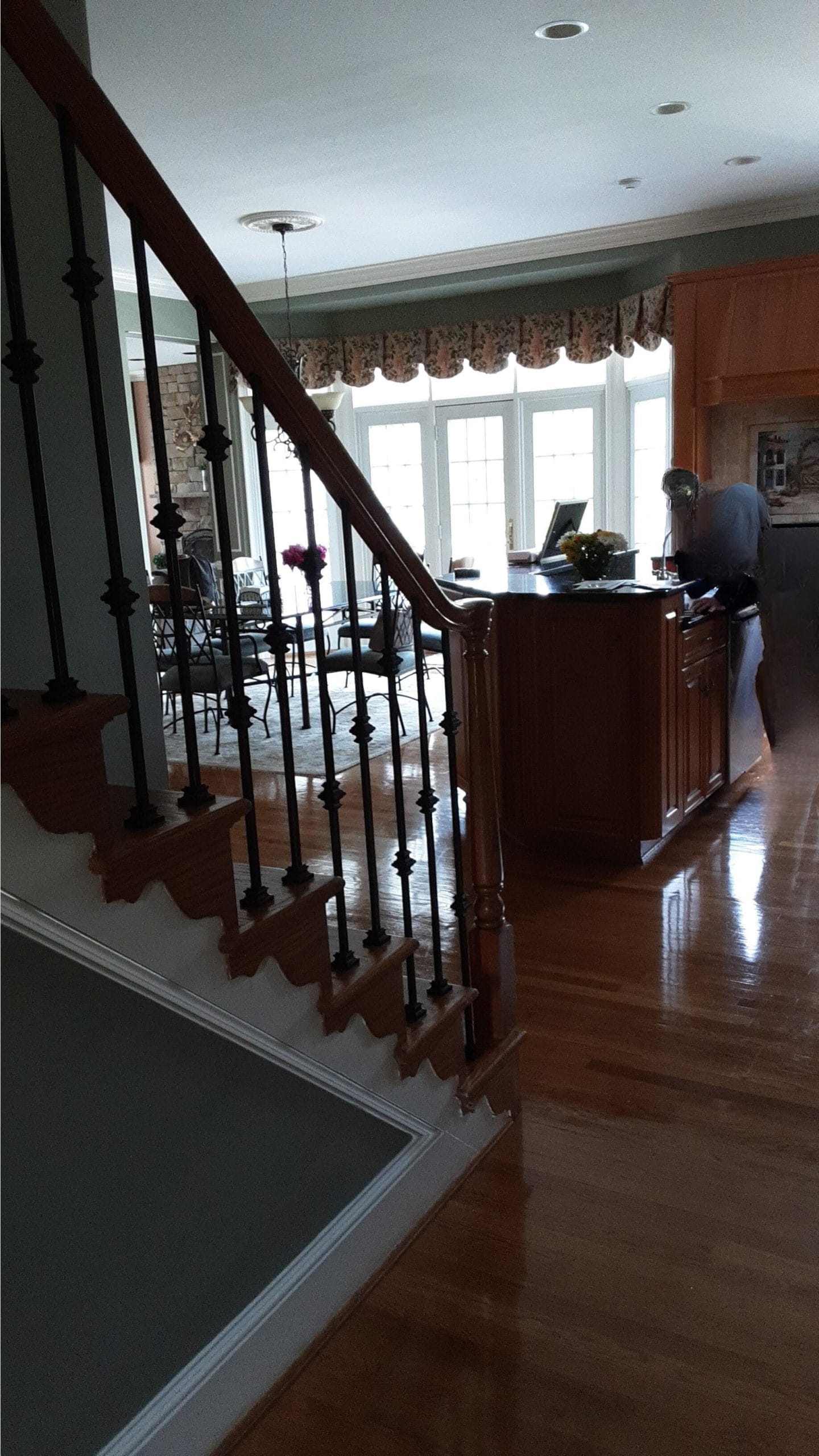 Before photo of a dark stair hall in a Northern Virginia colonial with heavy wood railing and dated carpet runner
