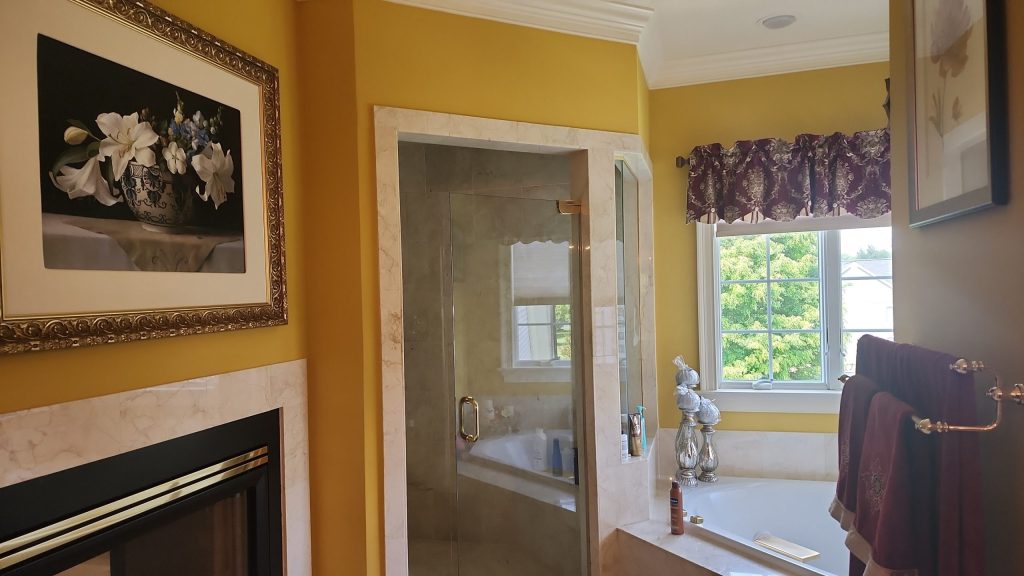 Before: a fireplace set into the bathroom wall next to the old framed glass shower door