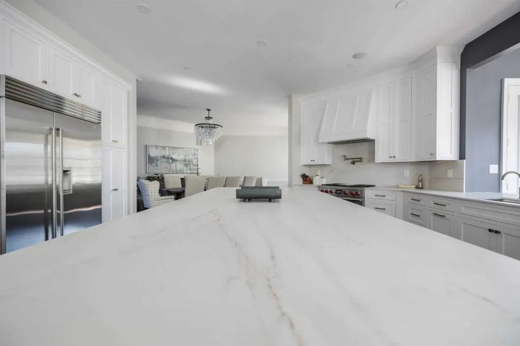 Modern white kitchen with marble countertops, stainless steel appliances, and elegant cabinetry.