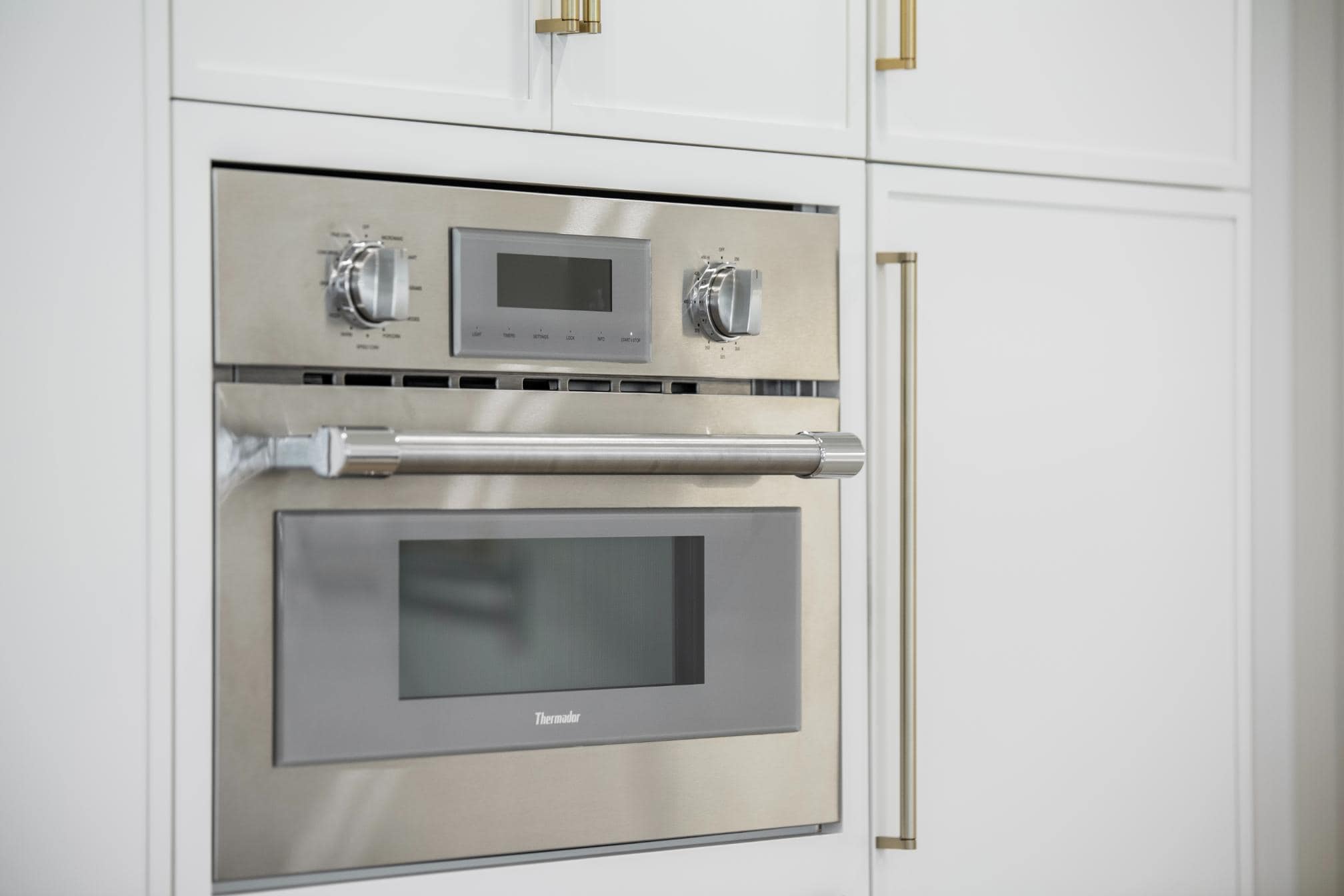 Sleek modern stainless steel oven integrated into white kitchen cabinetry
