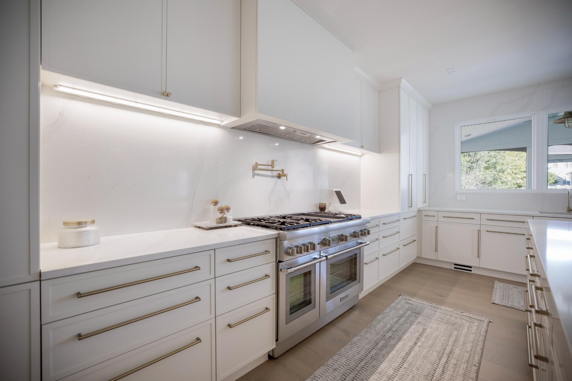 Contemporary white kitchen with sleek cabinetry, stainless steel appliances, and large windows, perfect for modern home design.