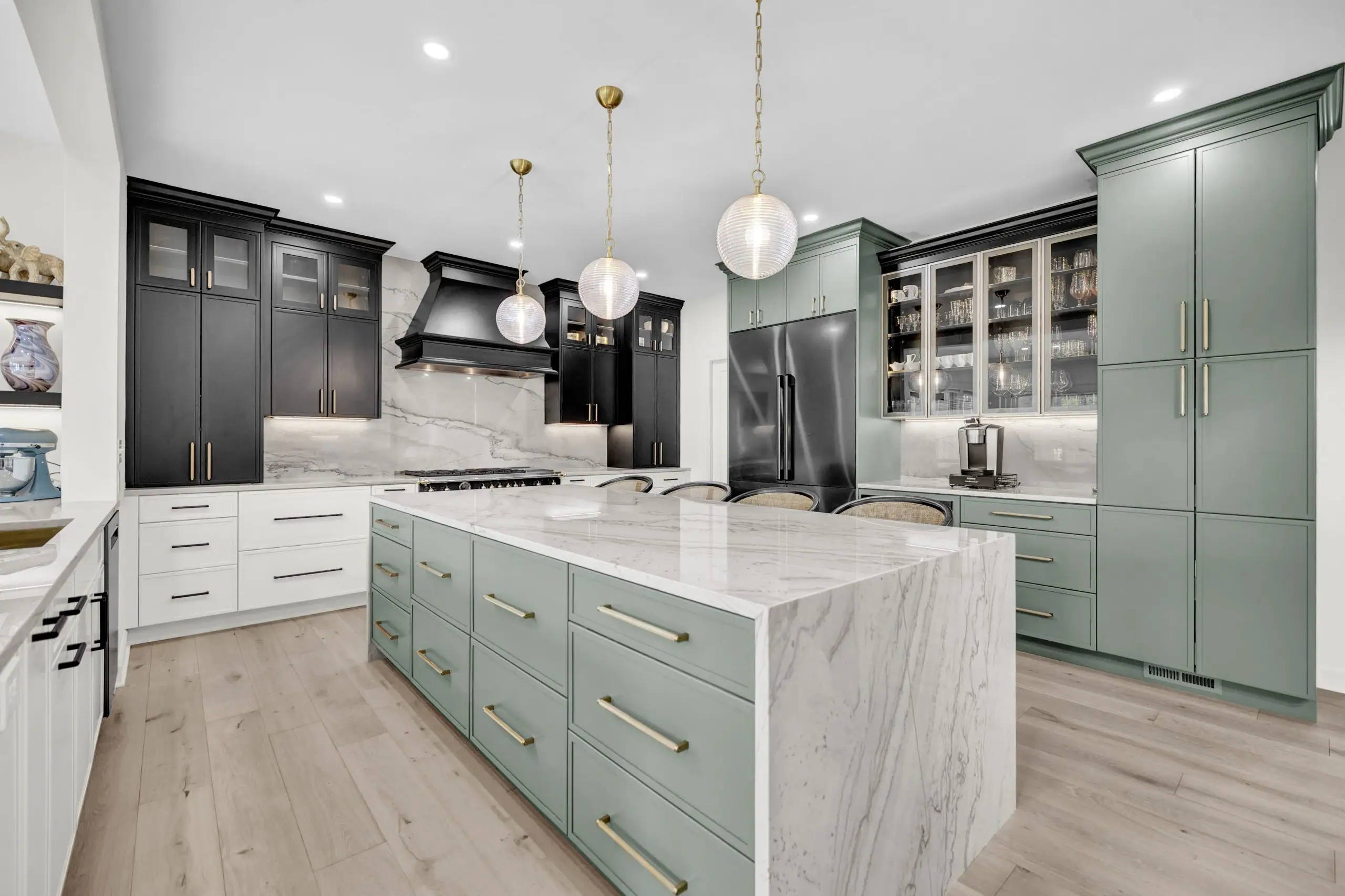 Kitchen with sage green cabinets, a black range wall and a marble waterfall island