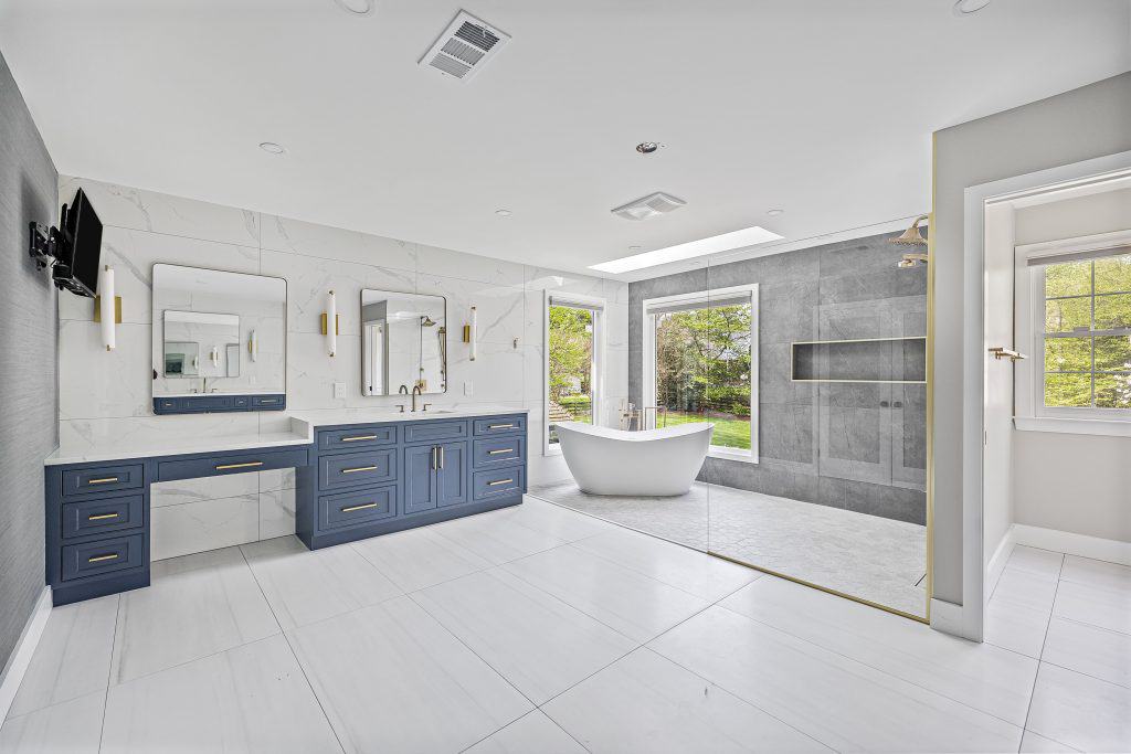Luxurious modern bathroom with blue cabinetry and freestanding bathtub.