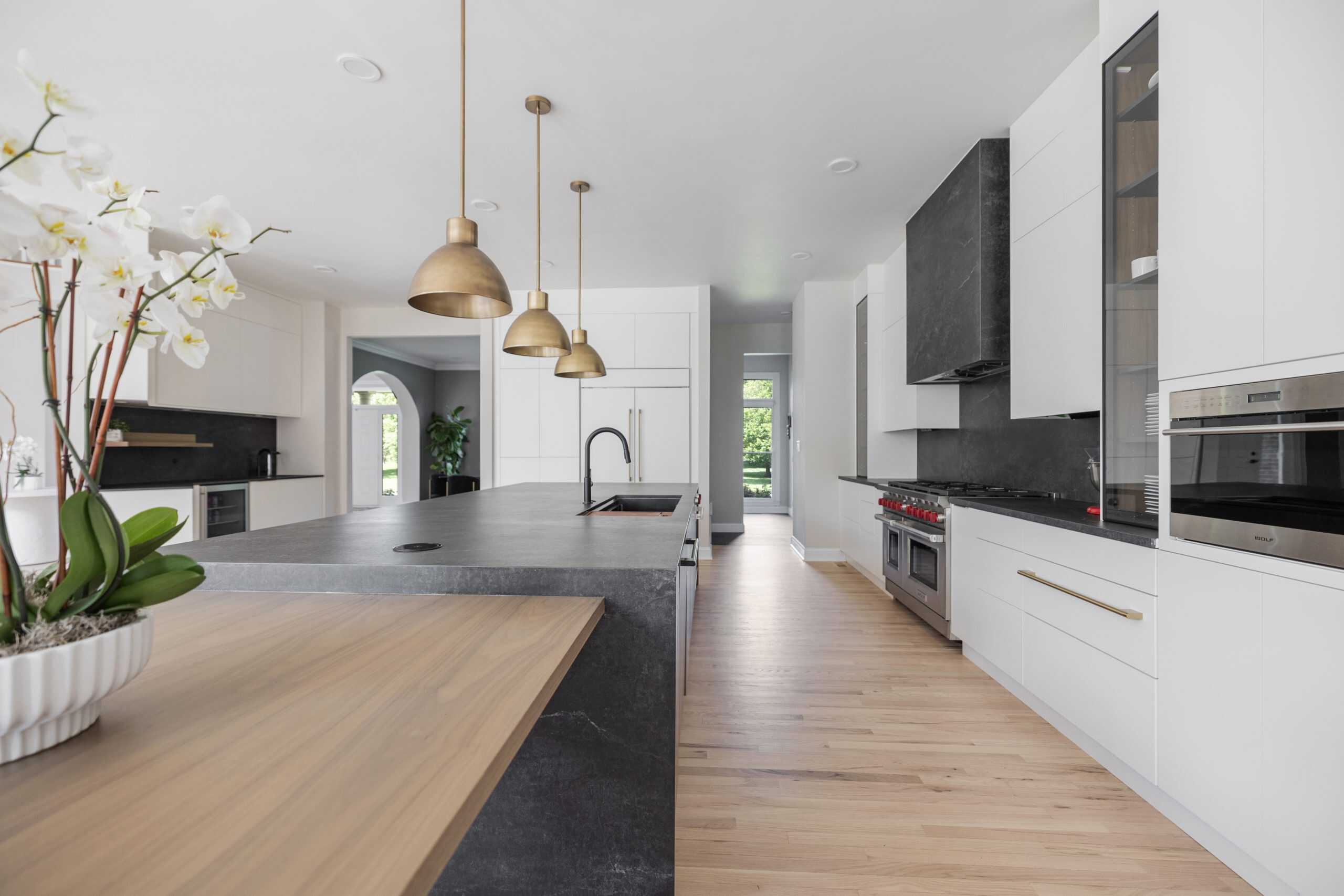 “Modern minimalist kitchen with smooth white cabinets, black accents on fixtures and trim, and wide natural wood flooring that adds warmth to the clean, simple design.