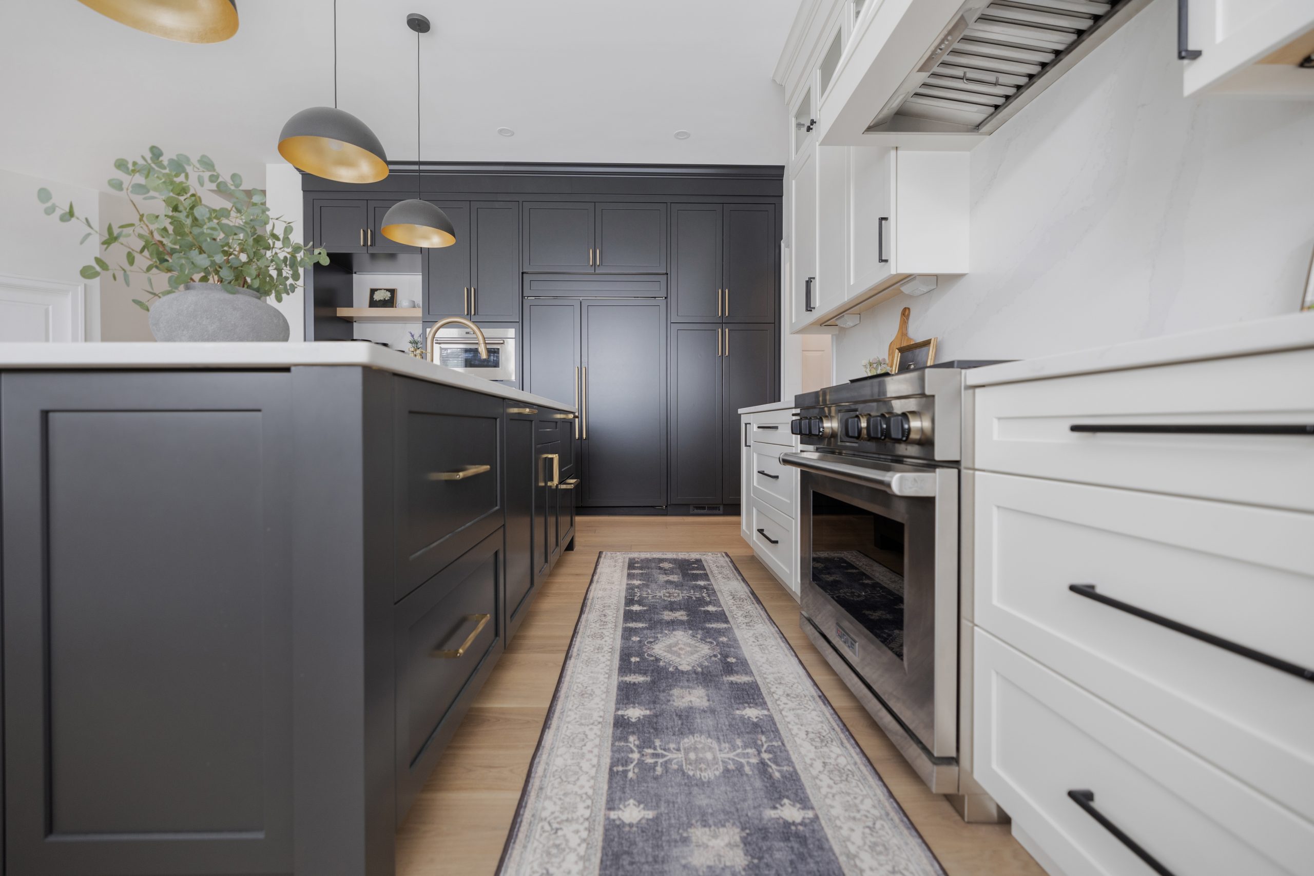 Modern black and white kitchen with gold accents, stylish cabinetry, and a patterned runner rug.