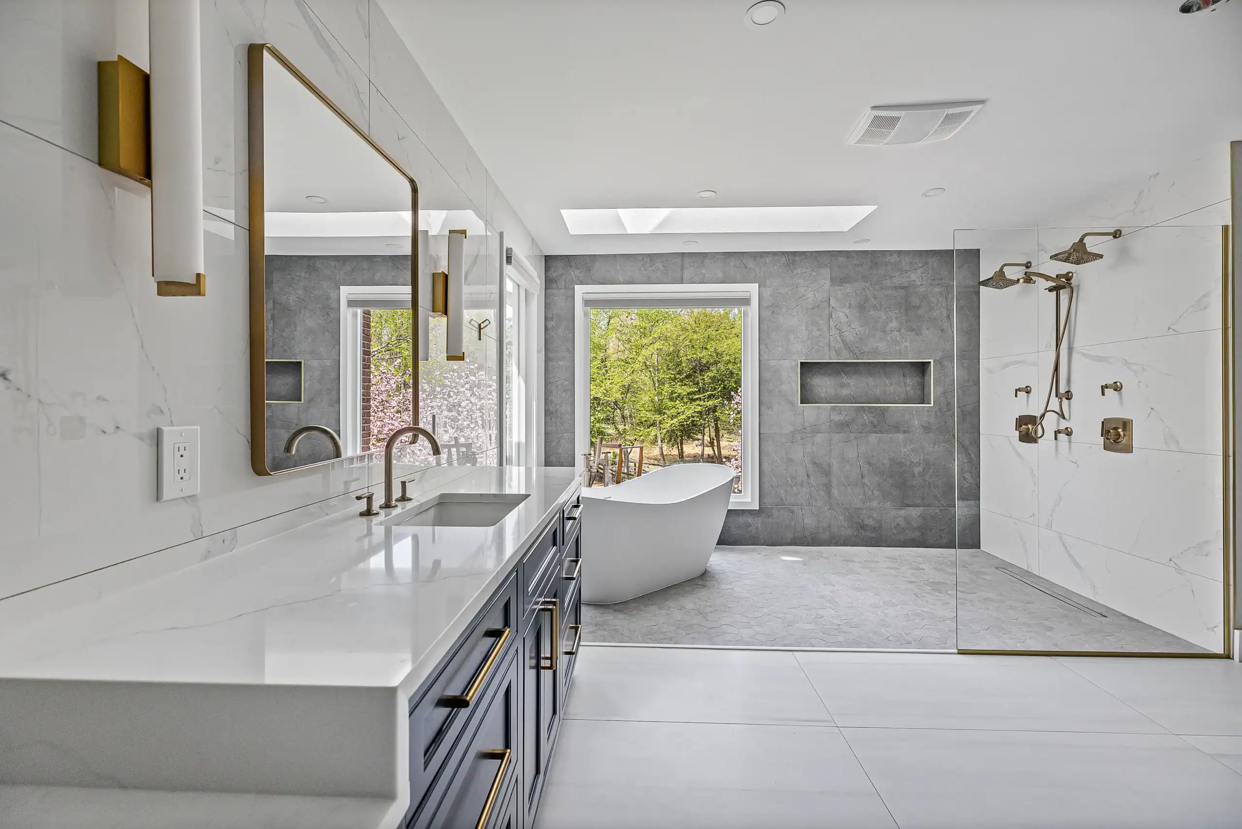 Luxurious modern bathroom with freestanding bathtub and walk-in shower, featuring elegant gray and white marble design.