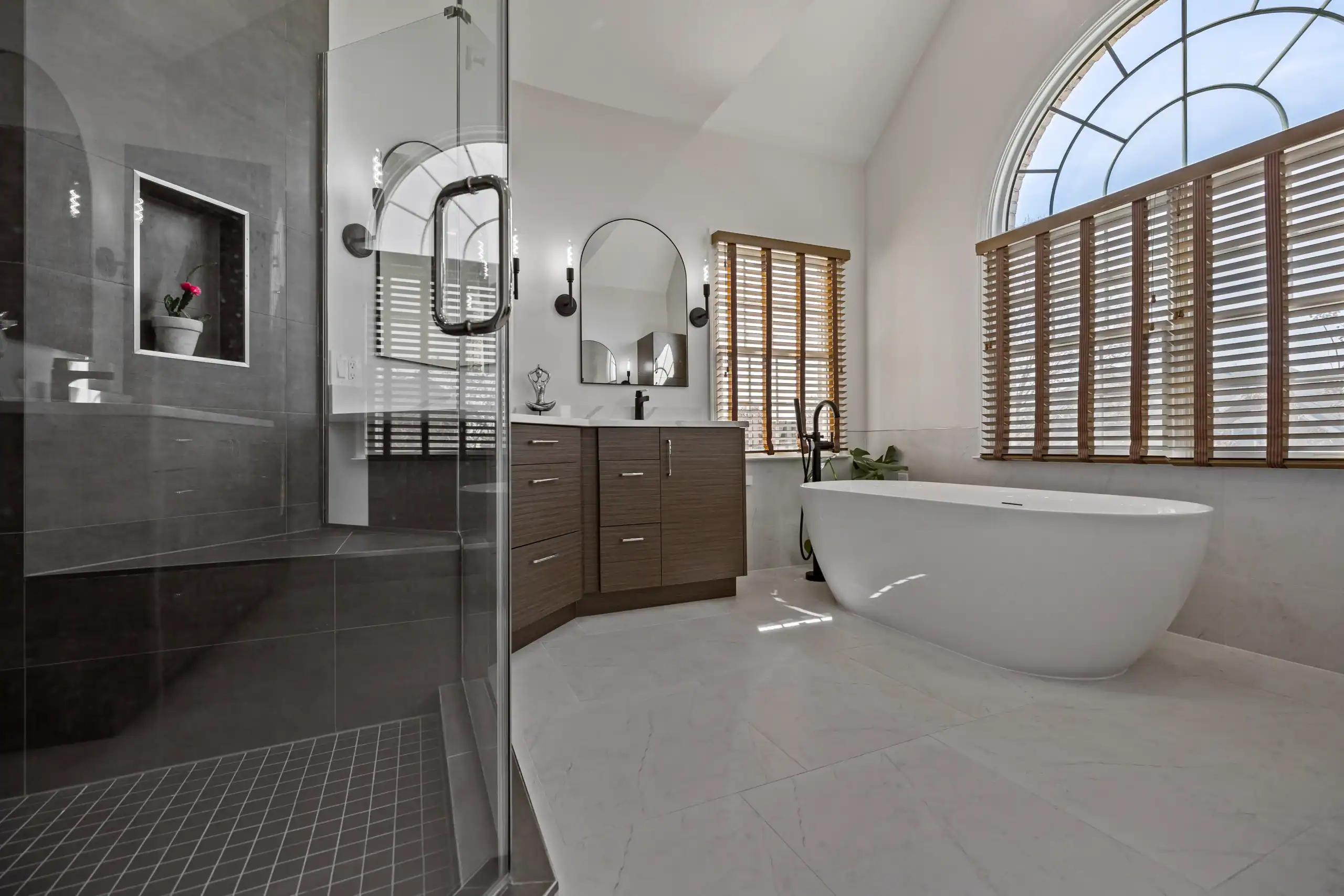 Spacious modern bathroom with freestanding bathtub and large arched window for natural light