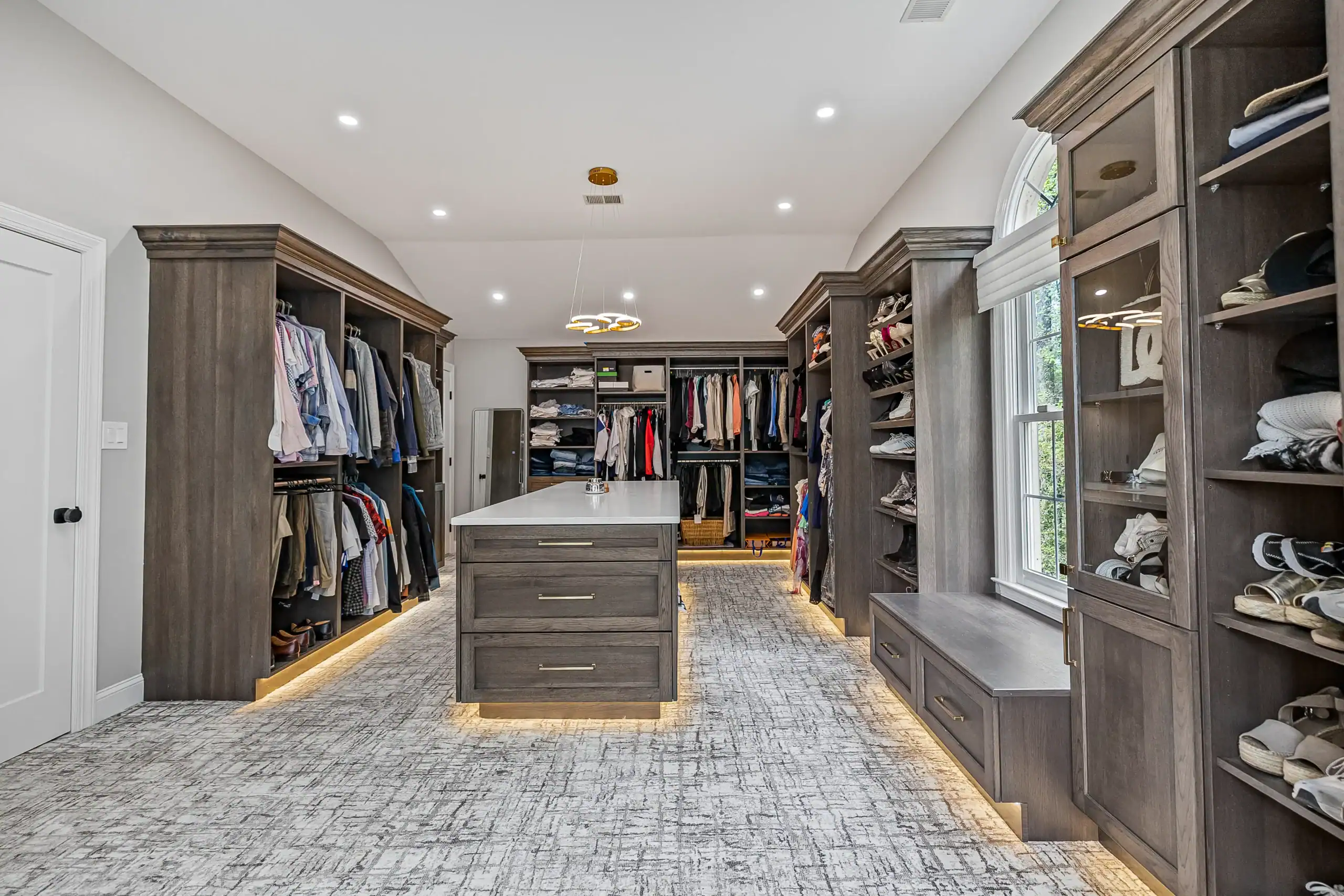 Luxurious walk-in closet with custom dark wood cabinetry and ample storage space
