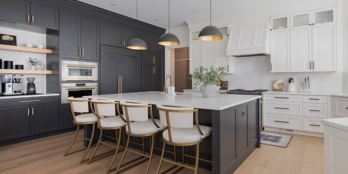 Modern kitchen with white and navy cabinetry, island, and contemporary lighting.