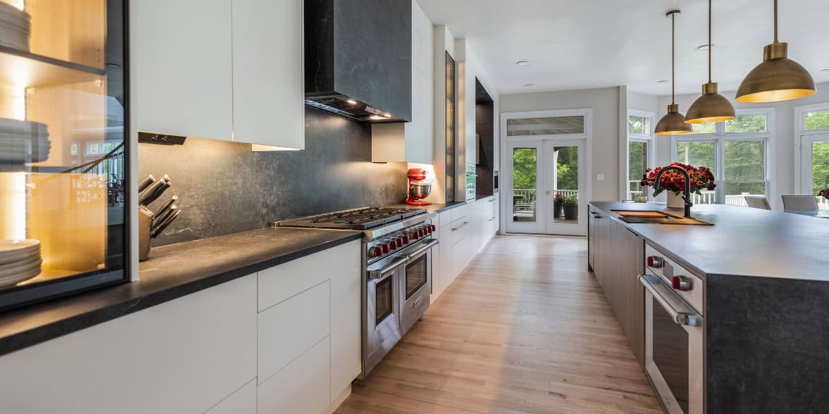 Modern kitchen with white cabinets, black countertops, and stainless steel appliances, ideal for contemporary home design.