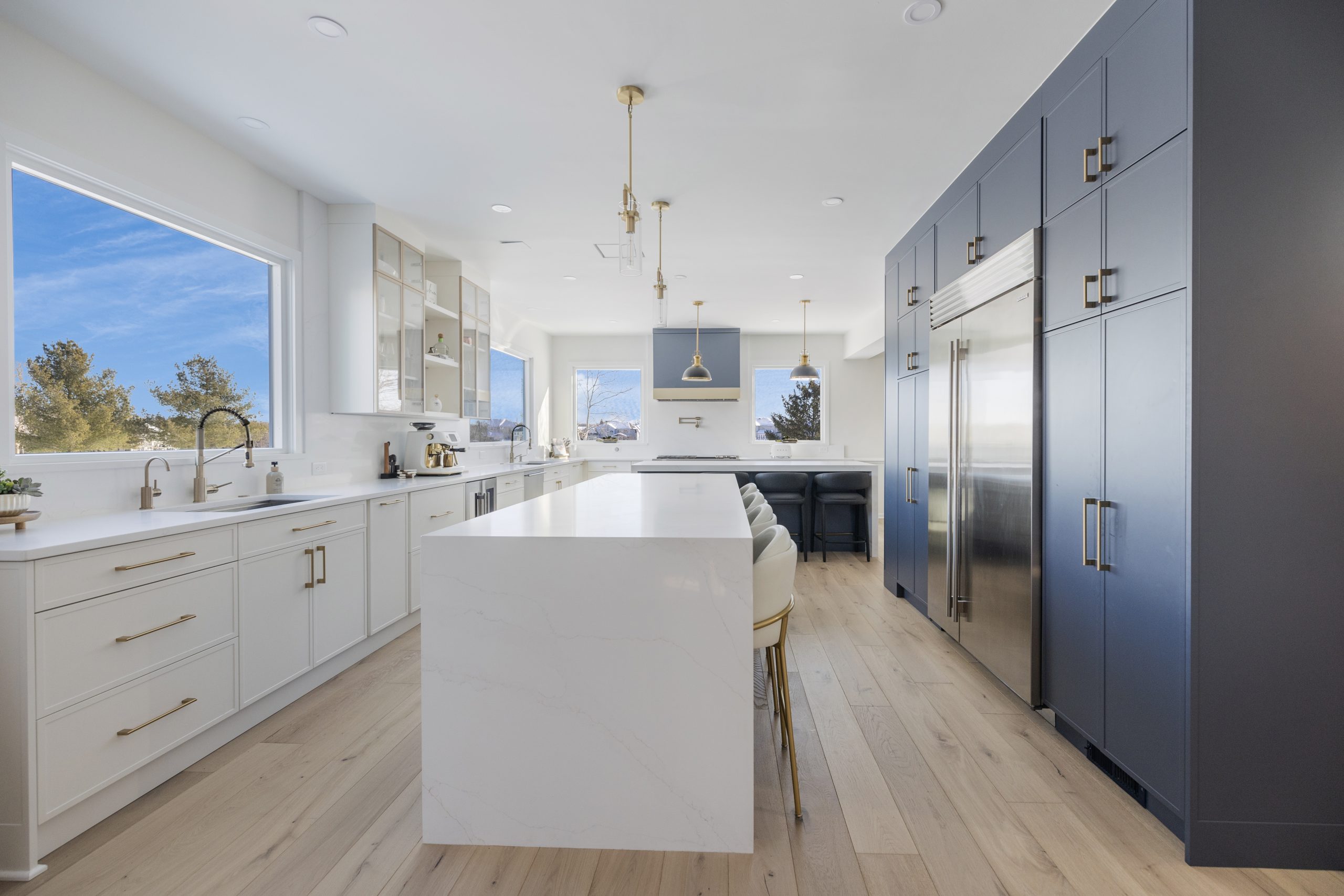 Navy blue transitional kitchen cabinets with white countertops and light wood floors